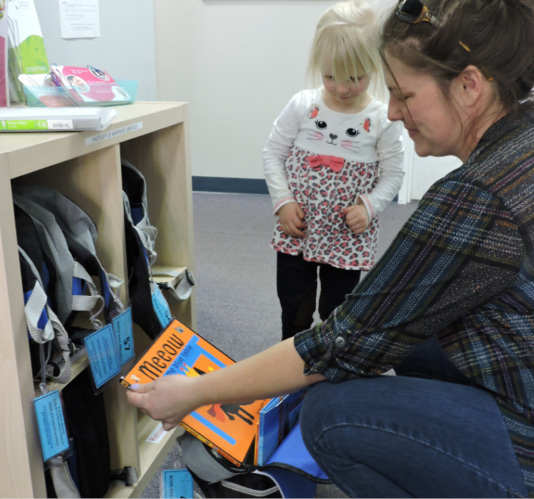 A parent and child check out book bags to share at home.