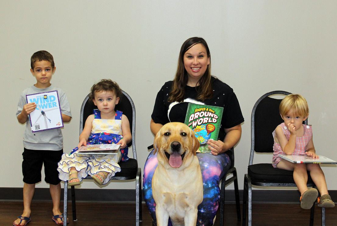 Librarian Laura Pitts poses with eager readers and man’s best friend Leo.