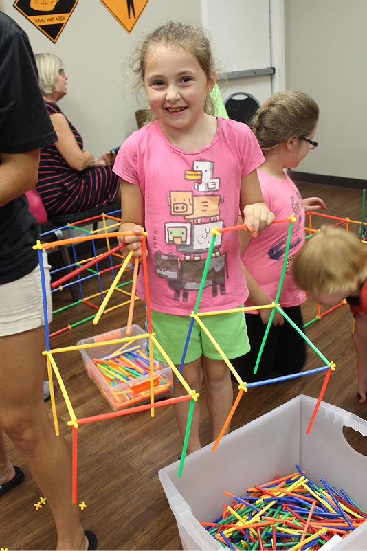 Girl holding two chair shapes she created with connectors.