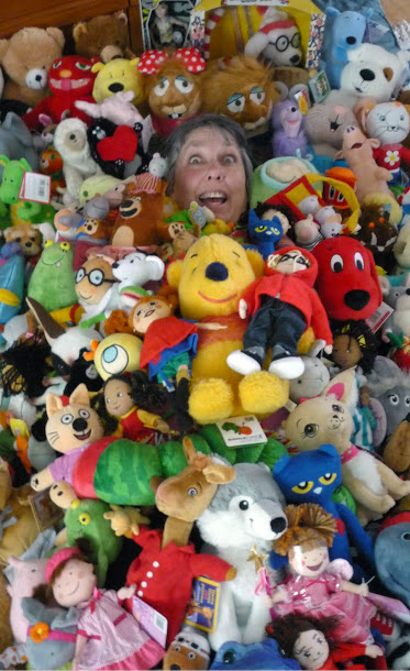 Stephanie Bange in a large pile of dolls and stuffed animals.