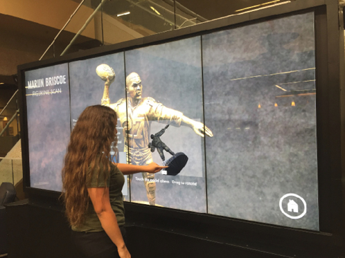 Figure 12. Student interacting with the UNO Libraries Archives and Special Collections Marlin Briscoe display by moving a 3D-scanned figurine from the collection. See the Marlin Briscoe online exhibit at unomaha.omeka.net/exhibits/show/briscoe/main. 